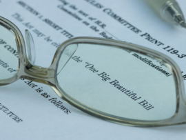 Glasses laying on paper showing "The Big Beautiful Bill"